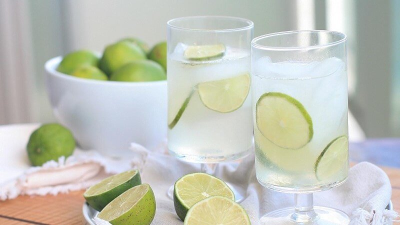 Hai ly nước chanh với lát chanh tươi, bên cạnh là bát đựng chanh nguyên trái trên bàn.