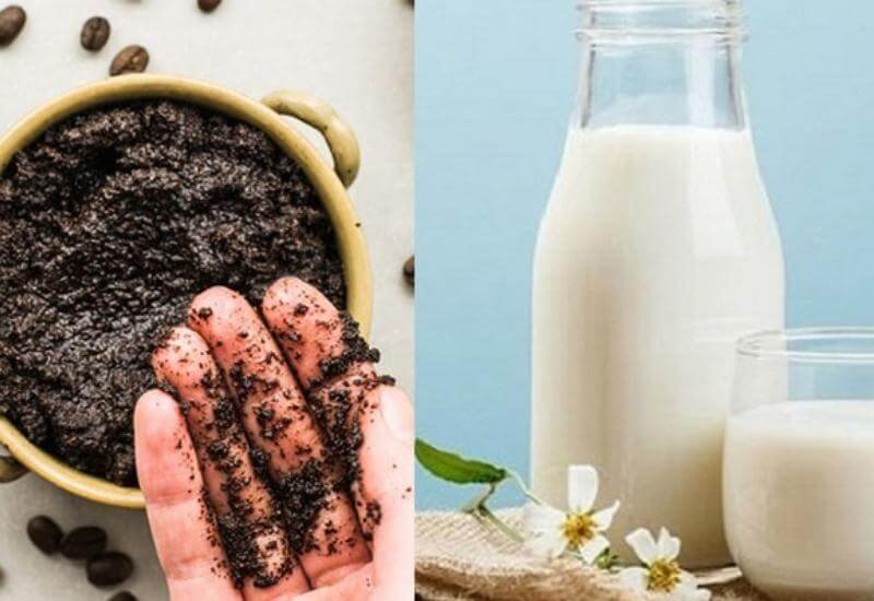 Một tay cầm bã cà phê cạnh ly và chai sữa trên nền xanh.