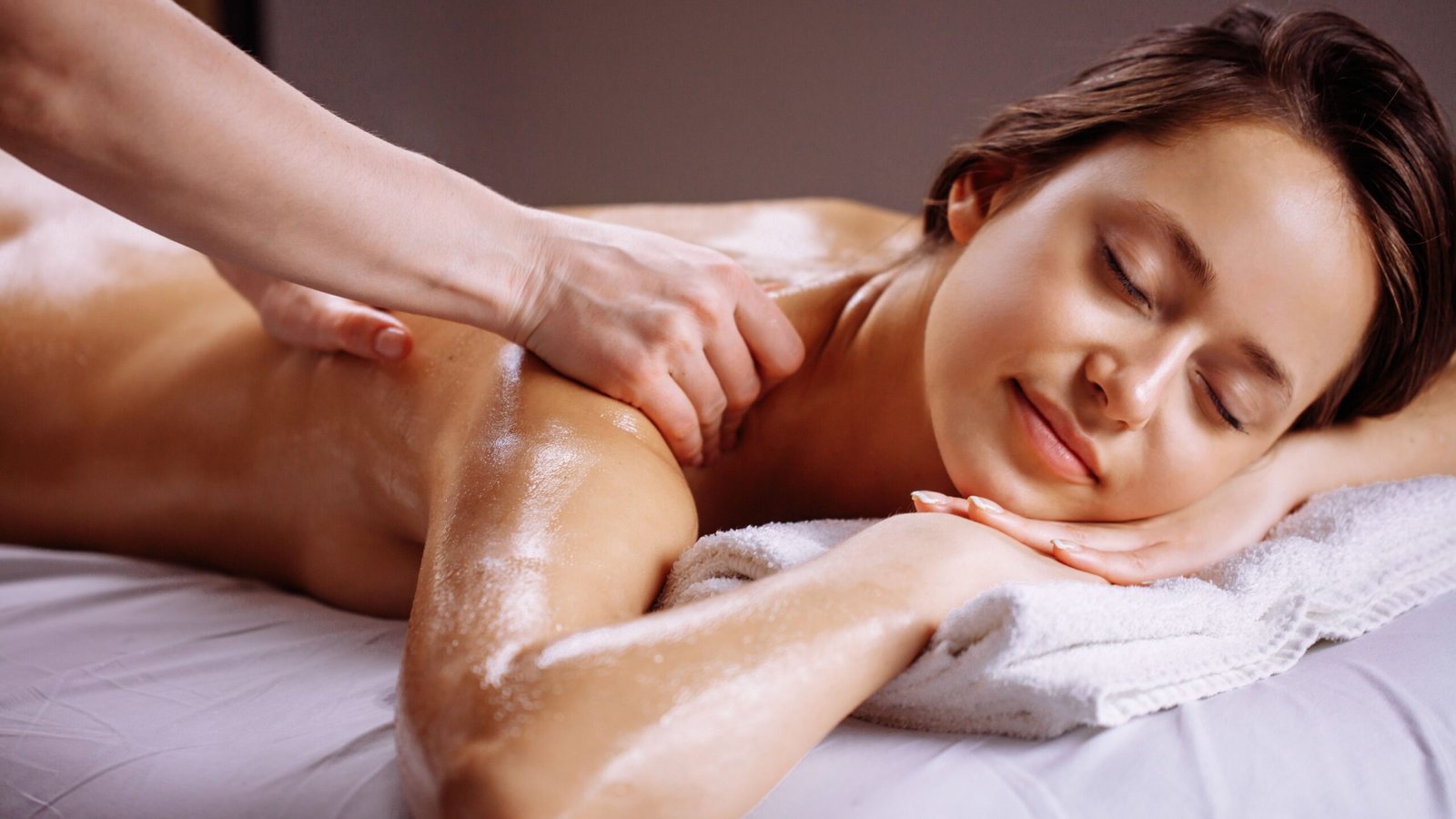 Top 20+ Địa Chỉ Massage Quận 3 Uy Tín, Chuyên Nghiệp 1 Người đang nhận liệu pháp mát-xa thư giãn trên giường, với khăn phủ và ánh sáng êm dịu.