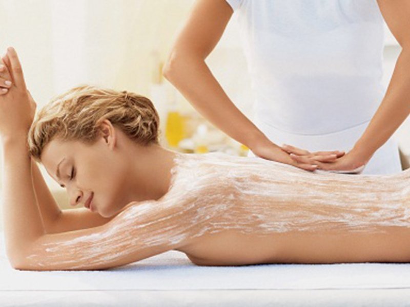 Người đang được massage lưng với kem dưỡng, tạo cảm giác thư giãn trong không gian spa sáng sủa.