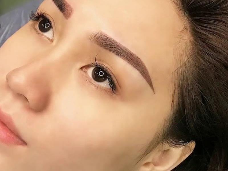 Gương mặt với đôi mắt to và lông mày đậm, nhìn nghiêng, trong khung cảnh ánh sáng dịu.