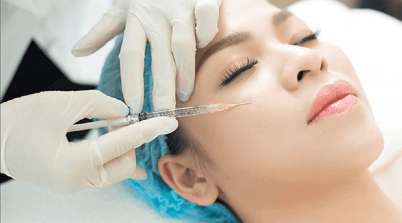 Người đeo găng tay y tế đang tiêm chất làm đầy vào vùng da gần mắt của một người đang nằm thư giãn.
