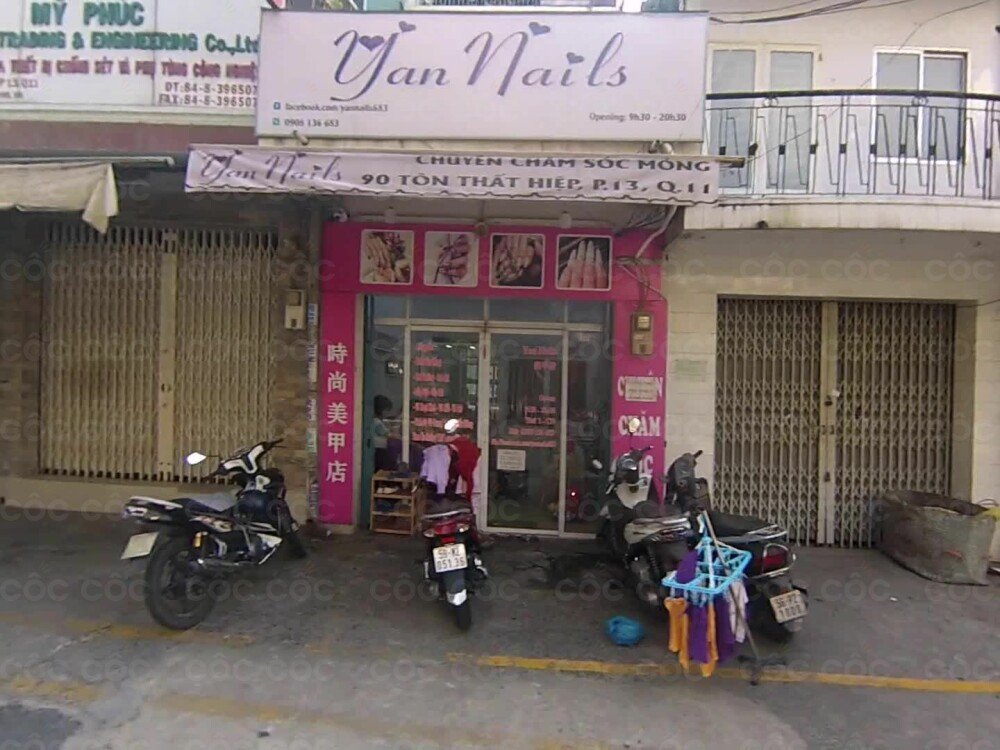 Top 10+ Tiệm Nail Quận 11 Đẹp, Chuyên Nghiệp Được Yêu Thích Hiện Nay 6 Mặt tiền tiệm làm móng với biển hiệu lớn, có xe máy đỗ phía trước và người đứng gần cửa kính.
